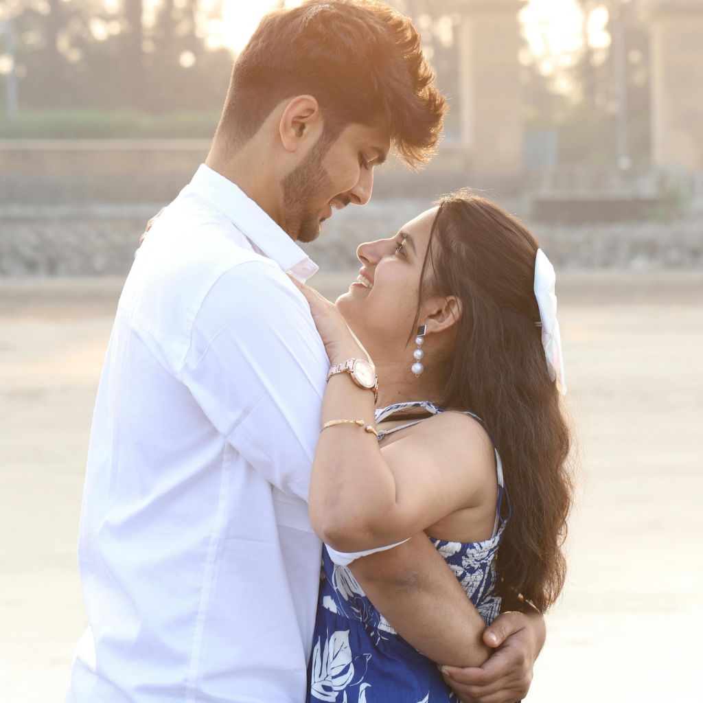 Couple embracing outdoors as they look lovingly into each other’s eyes in warm sunlight.