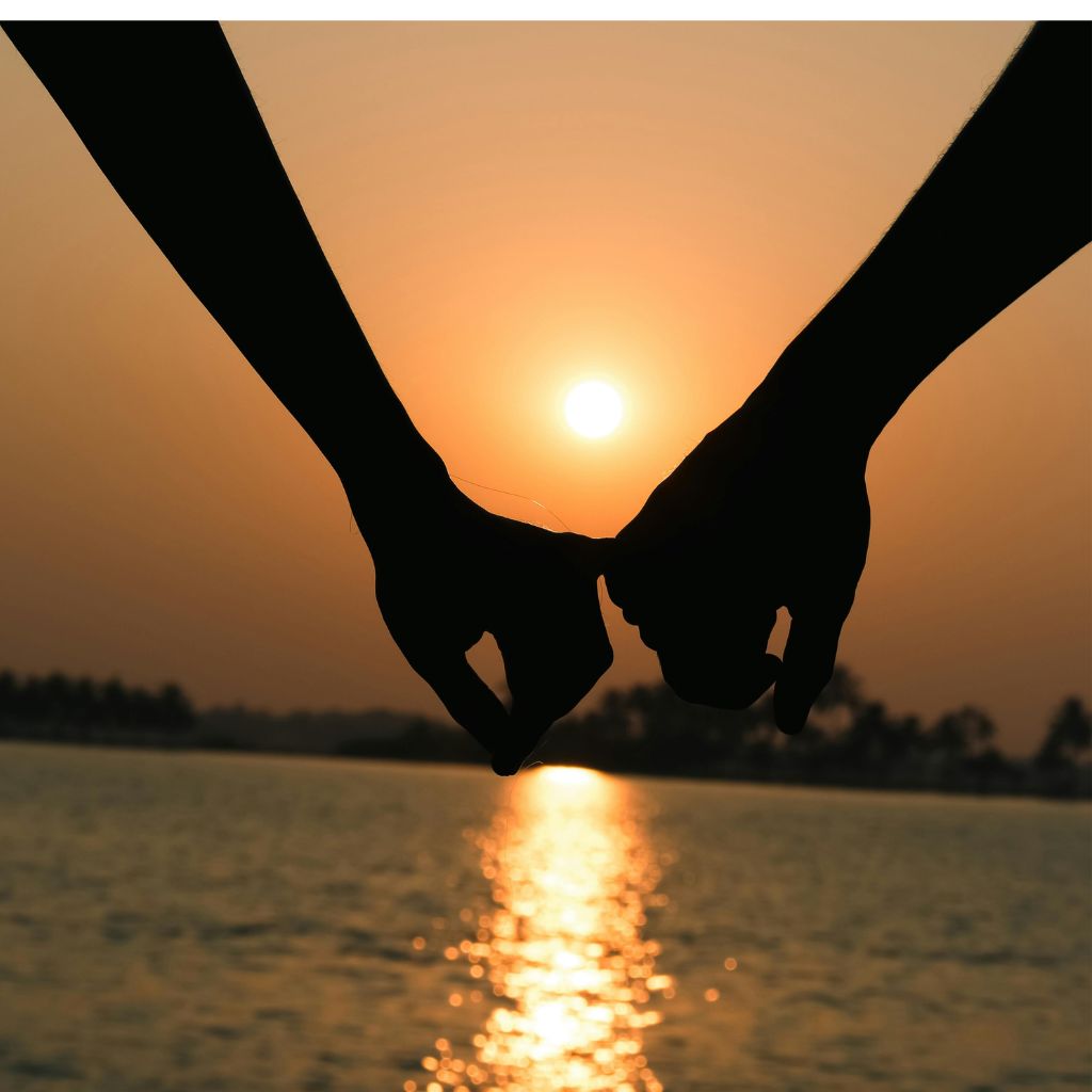 Couple holding hands at sunset by the water