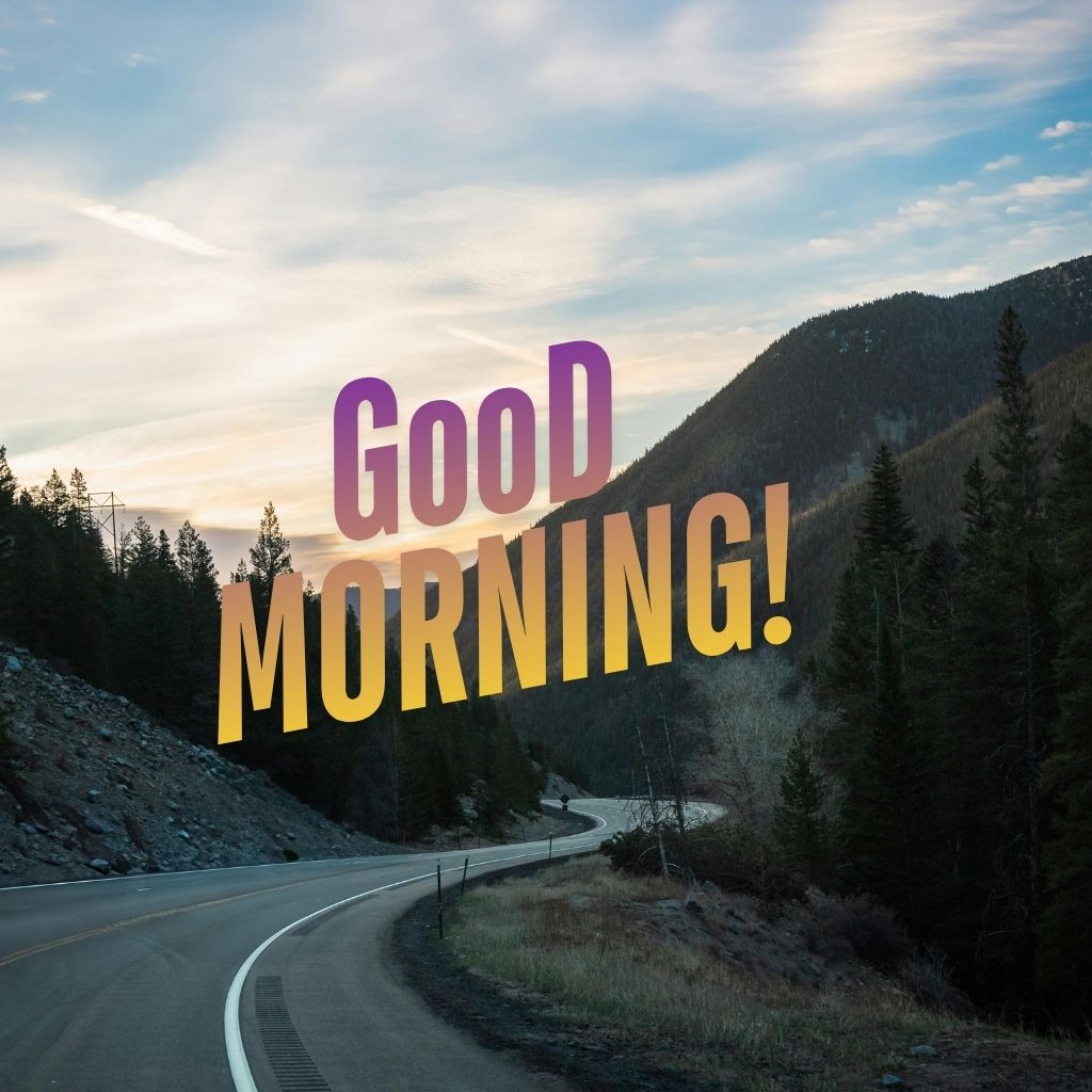 A cheerful 'Good Morning' text painted on a road, surrounded by greenery and a clear blue sky.