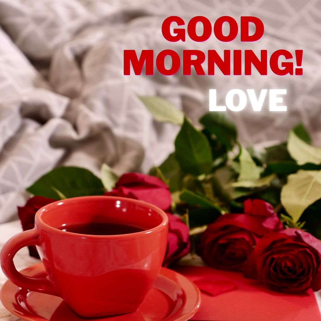 Red cup of coffee beside a bouquet of red roses on a cozy bed, with “GOOD MORNING! LOVE” written above.