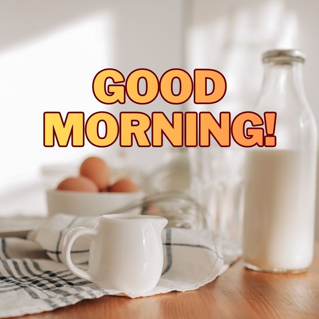 A glass milk bottle, white pitcher, and a bowl of eggs on a wooden table with bold text reading "GOOD MORNING!".