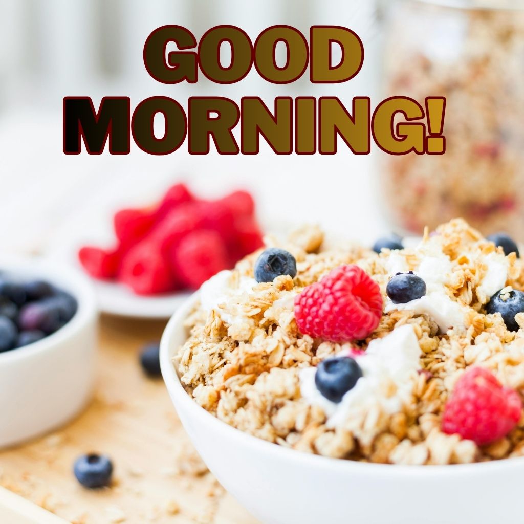 A white bowl filled with granola, yogurt, blueberries, and raspberries with bold text reading "GOOD MORNING!" overlaid above it.
