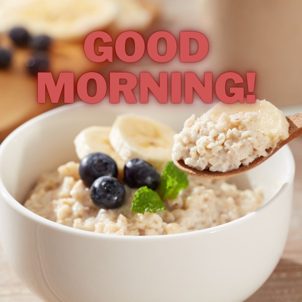 A bowl of oatmeal topped with banana slices and blueberries with a spoonful being lifted and bold text reading "GOOD MORNING!" across the top.